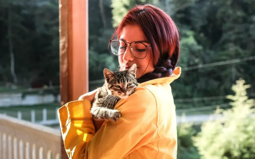 woman-in-yellow-raincoat-holding-cat-wont-leave-me-alone